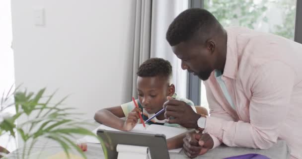 Afroamerikanischer Vater Hilft Sohn Hause Mit Tablet Bei Den Hausaufgaben — Stockvideo