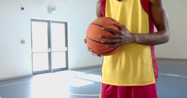 年轻的非洲裔美国人在体育馆里拿着一个篮球 有一个复制的空间 他的立场表明 他已经准备好参加一场比赛或练习赛 慢动作 — 图库视频影像