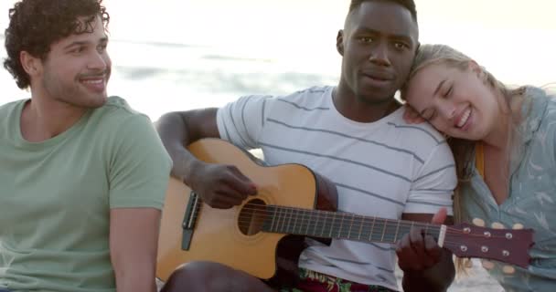 年轻的非裔美国人在海滩派对上弹吉他 白种人的男人和年轻的白人女人在放松的海滩环境和慢动作中欣赏音乐 — 图库视频影像