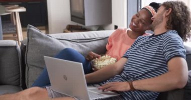 Çeşitli çiftler, genç bir Afro-Amerikalı kadın ve beyaz bir erkek, evde film izliyorlar. Kanepede patlamış mısır ve dizüstü bilgisayarla rahat bir anı paylaşıyorlar..