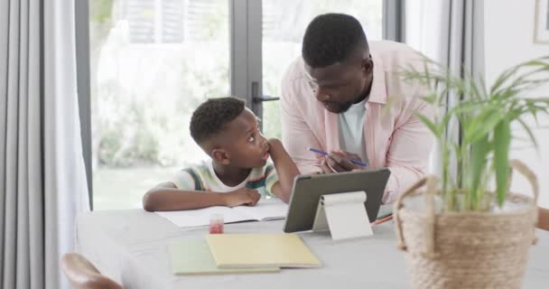 African American Man Helps Boy Homework Home Using Tablet Engaged — Stock Video