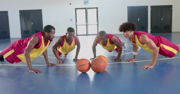 不同的篮球运动员在体育馆里做俯卧撑 他们的训练课程强调团队合作和在室内运动设施中的身体健康 以及慢动作 — 图库视频影像