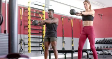 Spor salonunda kettlebell 'li çeşitli egzersizler. Dayanıklılık antrenmanına odaklanırlar. Formlarını artırırlar. Ağır çekimde..