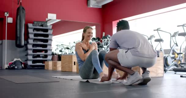 健康的非裔美国男子帮助年轻的白人女子在健身房 他们专注于健身训练 在有利的环境中增强核心肌肉 慢动作 — 图库视频影像