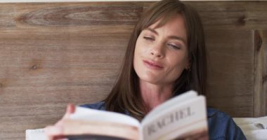 Evde kitap okuyan orta yaşlı, beyaz bir kadın. Güzel ve ağır çekimde sakin bir anın tadını çıkarıyor..