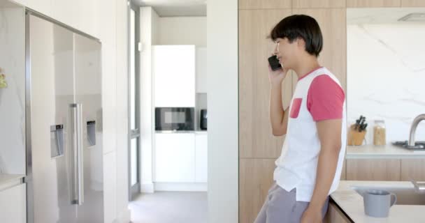 Teenage Asiatisk Gutt Nyter Drink Moderne Kjøkken Med Kopiering Plass – stockvideo