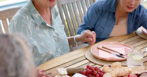 元老妇女与餐桌旁的某个人牵着手 在一个家庭的环境中 一个感恩或祈祷的时刻似乎被分享 缓慢的运动 — 图库视频影像