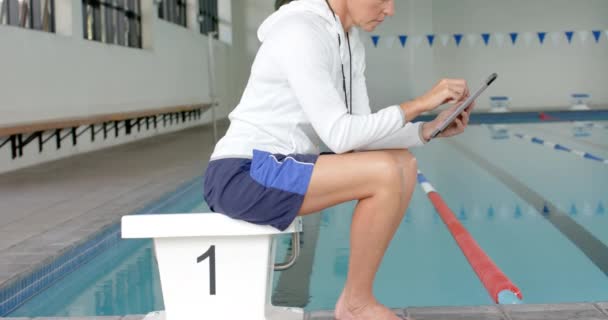 白种人教练在平板体上查看数据 她是一名教练 负责分析室内游泳设施的性能指标 以及慢动作 — 图库视频影像