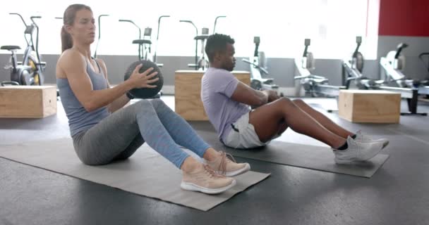 Spor Salonunda Tıp Topuyla Egzersiz Yapan Sağlıklı Beyaz Kadın Afrikalı — Stok video