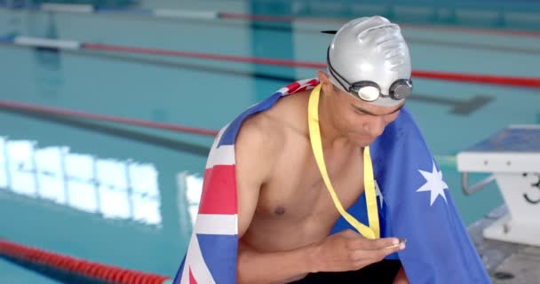 骄傲的游泳运动员拿着澳大利亚国旗在游泳池里展示他的金牌 他的成就突出表明了他在体育运动中的竞争精神和慢动作 — 图库视频影像