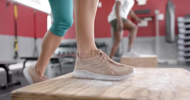 适合年轻的白人女子和非洲裔美国男子在健身房跳箱子 他们专注于高强度的体能训练 展示力量和决心 慢动作 — 图库视频影像
