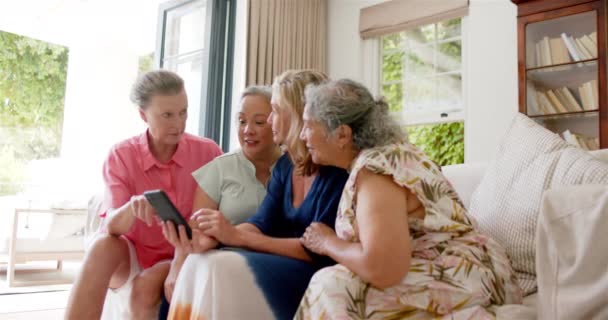 一群来自不同地区的资深女性使用智能手机在家中共度时光 当他们聚集在一起 分享回忆或新闻 慢动作时 兴奋的气氛弥漫在空气中 — 图库视频影像