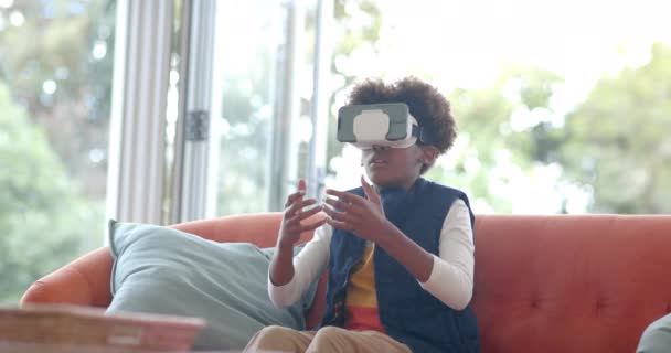 Afrykański Amerykański Chłopiec Siedzi Kanapie Używając Zestawu Słuchawkowego Dotykając Wirtualnego — Wideo stockowe