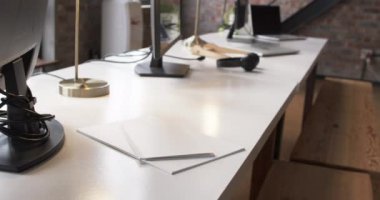 Modern bir ofis masası bilgisayar, lamba ve kulaklıkla donatılmıştır. Ayarlar, minimal tasarım, yavaş çekim odaklı çağdaş bir çalışma alanı öneriyor.