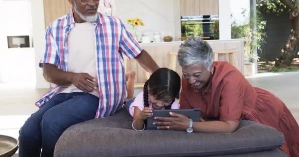 Abuelos Birraciales Están Participando Con Una Niña Usando Una Tableta — Vídeos de Stock
