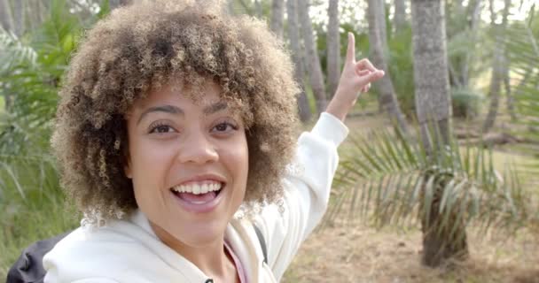 Young Biracial Woman Curly Hair Smiles Brightly Pointing Upwards Surrounded — Stock Video