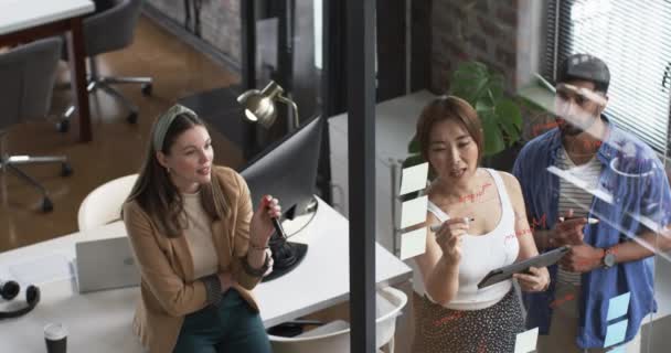 年轻的高加索女人和亚洲女人在办公室里和年轻的亚洲男人讨论生意 三人似乎参与了一个协作工作会议 使用了文档和数字平板电脑 — 图库视频影像