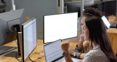 İki iş adamı bir iş ofisindeki bilgisayar ekranlarındaki verileri analiz ediyor. Görevlerine odaklanmaları, modern işyerlerinin işbirlikçi doğasını, ağır çekimleri vurgular..