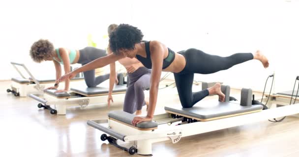 Dwurasowa Kobieta Wykonuje Ćwiczenia Pilates Maszynie Reformatorskiej Jej Skupienie Forma — Wideo stockowe