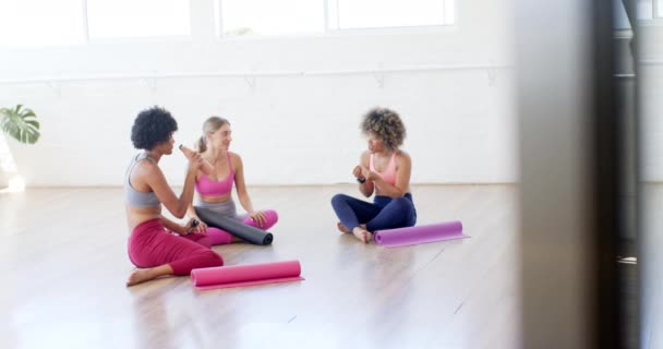 Tres Mujeres Relajan Colchonetas Yoga Charlando Estudio Luminoso Comparten Momento — Vídeos de Stock