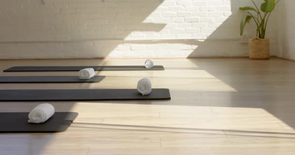 阳光沐浴在一个宁静的瑜伽工作室 带着滚动的垫子在木制地板上 有复制的空间 温暖的氛围暗示着一种平静的放松 慢动作的环境 — 图库视频影像