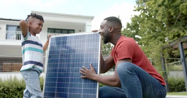 非洲裔美国人的父亲和儿子高五在一个太阳能电池板外 在家里 他们正在参与一个可持续的能源项目 促进环保意识和慢动作 — 图库视频影像