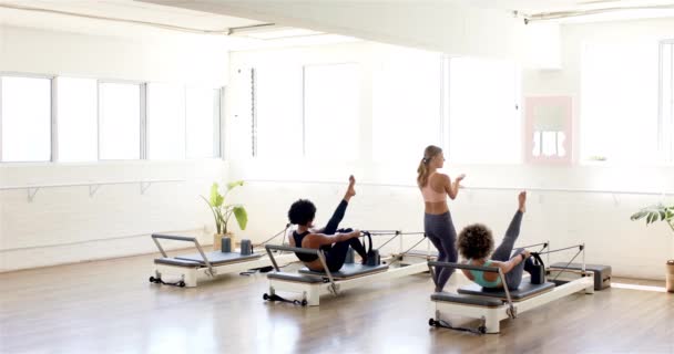 Three Women Exercising Pilates Reformer Machines Bright Studio Young Caucasian — Stock Video