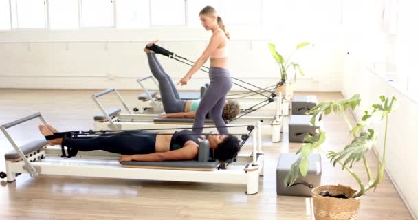 Three Women Exercising Pilates Reformer Machines Bright Studio Young Caucasian — Stock Video