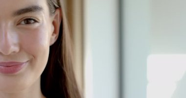 Kafkasyalı, hoş bir gülüşü ve kahverengi saçları olan evinde fotokopi alanı olan genç bir kızın yakın çekimi. Parlak ifadesi ve günlük tarzı rahat ve mutlu bir anı işaret ediyor, ağır çekim..