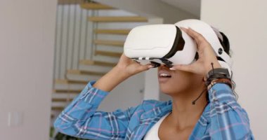 Genç bir Afrikalı Amerikalı kadın evdeki bir kanepede kulaklıkla sanal gerçekliği keşfediyor. Saçları örgülü, günlük kıyafetler giyiyor ve ağır çekimde bir VR kulaklıkla meşgul.
