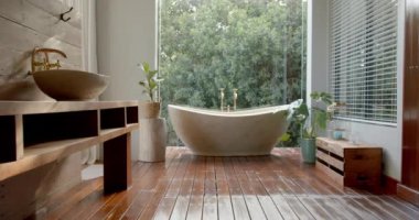 Modern bir banyoda serbest banyo küveti ve damar lavabosu olan ahşap bir kibir vardır. Geniş pencereler dışarıdaki yeşilliği gösteriyor, dingin ve doğal bir ortam yaratıyor..