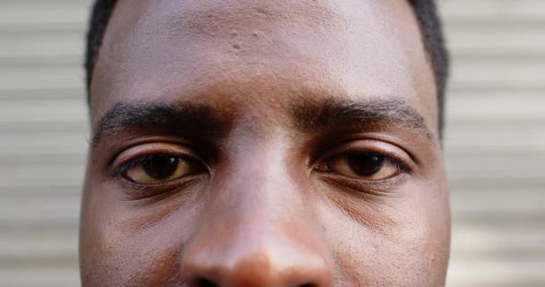 若いアフリカ系アメリカ人の目と額を閉じる 焦点は ぼやけたストライプの背景 ゆっくりとした動きに対する彼の視線と顔の特徴にあります — ストック動画