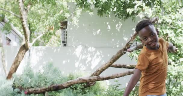Afrikkalainen Amerikkalainen Poika Jolla Leikkisä Ilme Seisoo Puun Lähellä Yllään — kuvapankkivideo