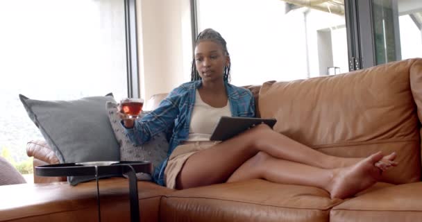 Nuori Afroamerikkalainen Nainen Nauttii Teetä Tabletin Käytön Aikana Hän Punottu — kuvapankkivideo