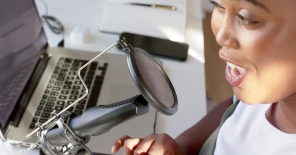 Афроамериканка Говорит Микрофон Записывая Подкаст Дома Находится Столом Ноутбуком Предполагая — стоковое видео
