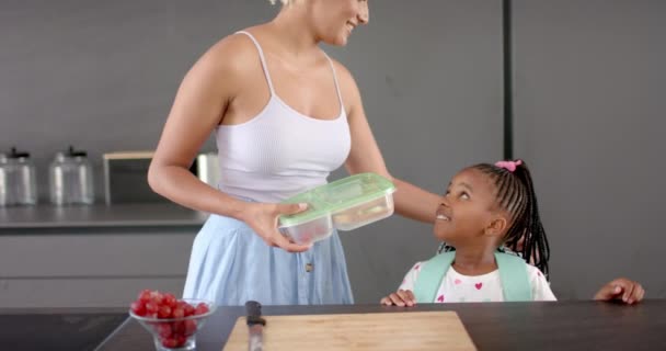 Молодая Двуличная Мать Держащая Контейнер Улыбается Афроамериканской Дочери Кухне Дома — стоковое видео