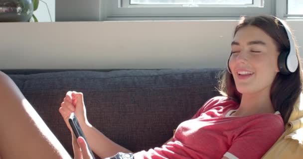 Teenage Caucasian Girl Enjoys Music Her Headphones Holding Smartphone Home — Stock Video