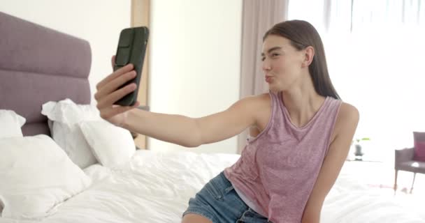 Teini Ikäinen Valkoihoinen Tyttö Ottaa Selfien Iskee Leikkisästi Silmää Puhelimeensa kuvapankin filmiä