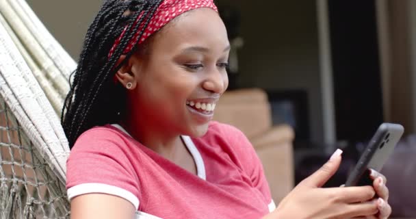 Молодая Афроамериканка Расслабляется Гамаке Заднем Дворе Используя Смартфон Плетеные Волосы — стоковое видео