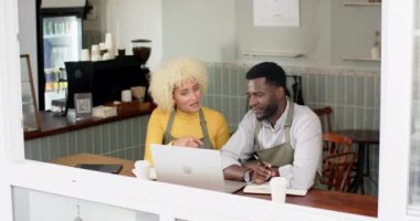 Genç bir Afro-Amerikalı erkek ve melez bir kadından oluşan bir barista ekibi bir kafede dizüstü bilgisayar üzerinde tartışıyor. Gri bir önlük giyiyor. Kahveci olabileceğini söylüyor. Kadın sarı bluzlu, sohbete dalmış..