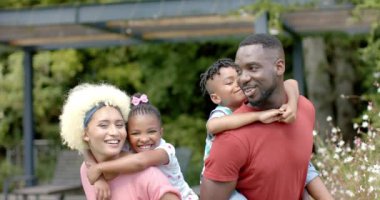 Genç melez bir kadın ve iki çocuğu olan Afro-Amerikan bir adamın mutlu ailesi evde gülümsüyor. Aile birlikte güneşli bir günün tadını çıkarıyor. Erkek ve kadın çocuklara sevgi gösteriyor..