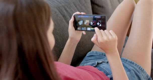 Teini Ikäinen Valkoihoinen Tyttö Pelaa Peliä Älypuhelimellaan Istuu Mukavasti Kotona — kuvapankkivideo