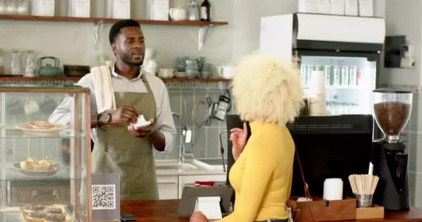Молодой Афроамериканец Бариста Обслуживающий Клиентов Кафе Тепло Улыбается Надевая Зеленый — стоковое видео