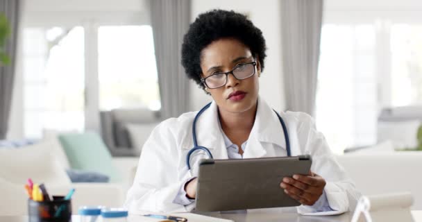 白いラボコートのアフリカ系アメリカ人女性医師は ビデオ通話相談でタブレットをレビューします 彼女は集中しているように見えます オフィスの設定で患者の情報を分析する医師 スローモーション — ストック動画
