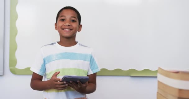Biracial Gutt Med Stripete Skjorte Holder Tablett Skolen Smilende Klasserom – stockvideo