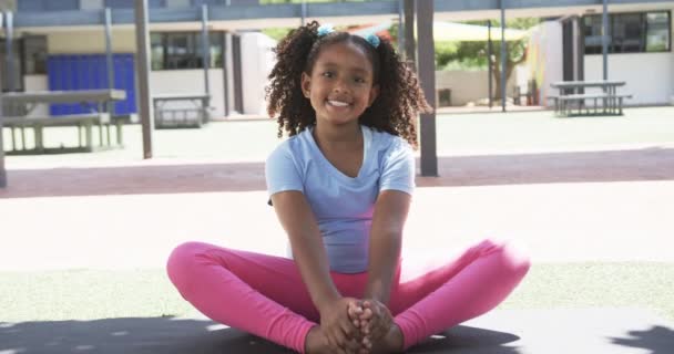 Dwurasowa Dziewczyna Kręconymi Włosami Siedzi Uśmiechnięta Szkolnym Podwórku Nosząc Niebieską — Wideo stockowe