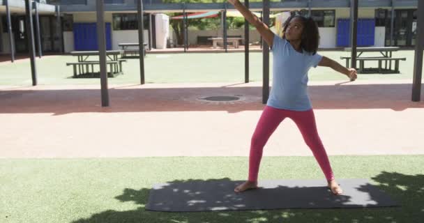 Biracial Jente Øver Yoga Utendørs Matte Med Kopiering Plass Skolen – stockvideo