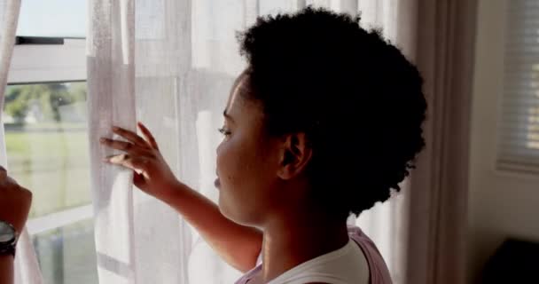 アフリカ系アメリカ人の女性は 自宅の窓から日光を楽しんでいます 彼女の閉ざされた目と穏やかな表情は 平和的な反射 ゆっくりとした動きの瞬間を示唆しています — ストック動画