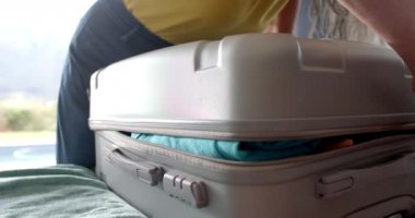 Olgun, beyaz bir kadın bavulunu emniyete alıyor. Altın bir bileziği var ve seyahat etmek için rahat giyinmiş, ağır çekimde, değişmemiş..