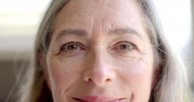 Yetişkin, beyaz bir kadının samimi bir şekilde gülümsemesini çek. Yüzünde kırışıklık ve yaşlanma belirtileri var. Gri saçlı, mavi gözlü, ağır çekimde, değişmemiş..